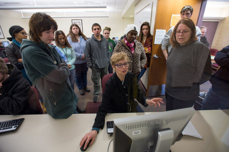 Instructor demonstrating computer application with group of students watching behind her