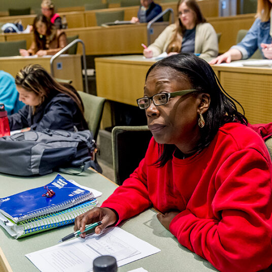 Older female wearing red focused in class