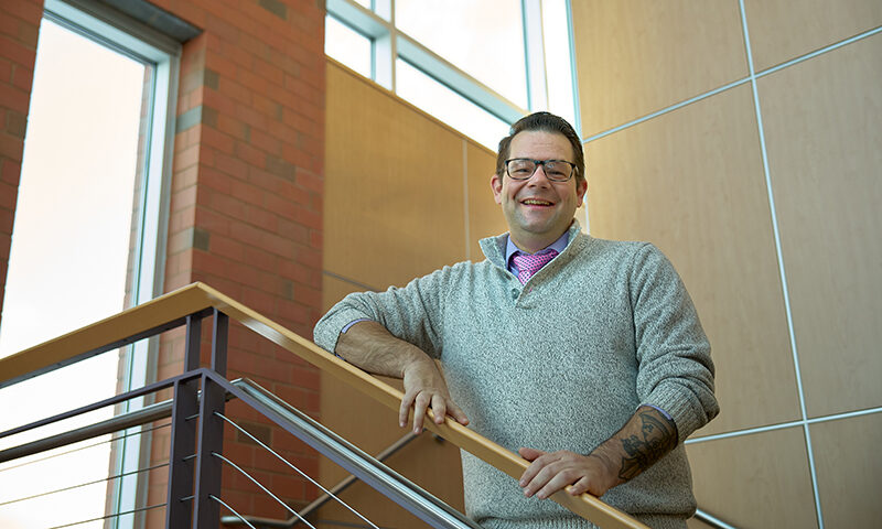 Photo of smiling male, standing in stairwell