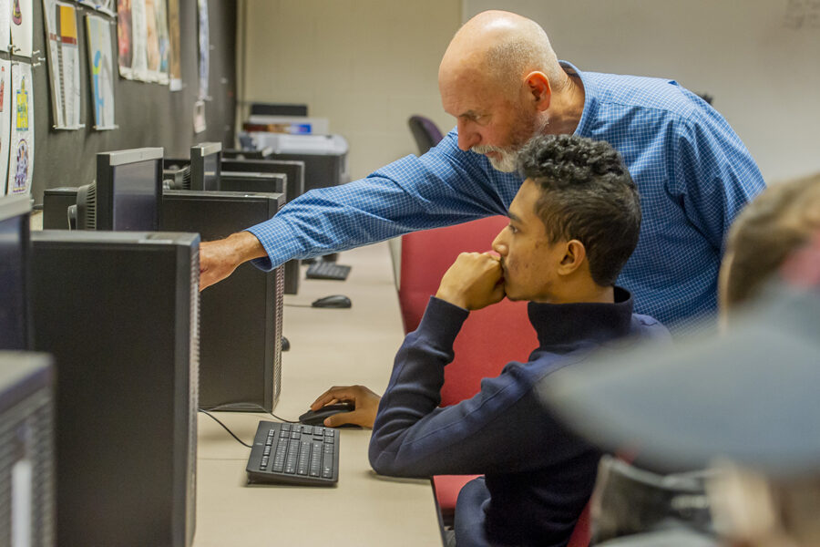 Male instructor helping student navigate computer