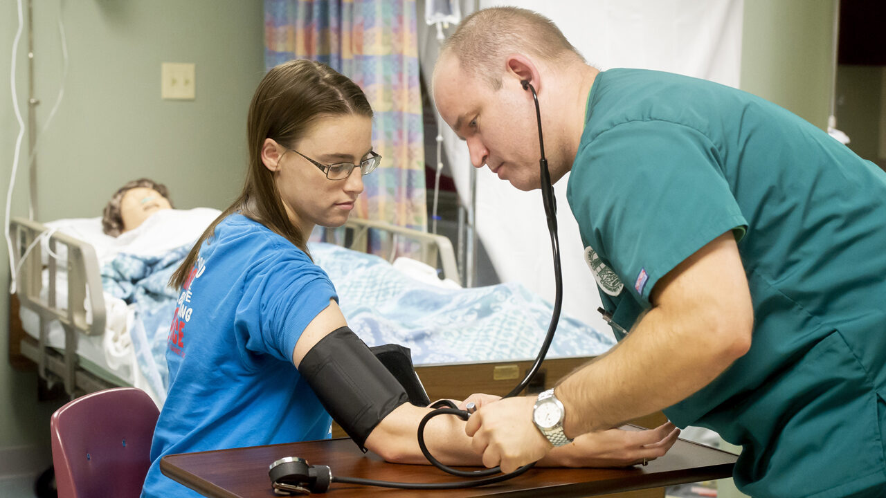 White male nursing students taking blood pressure on white female