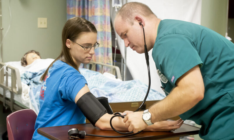 White male nursing students taking blood pressure on white female