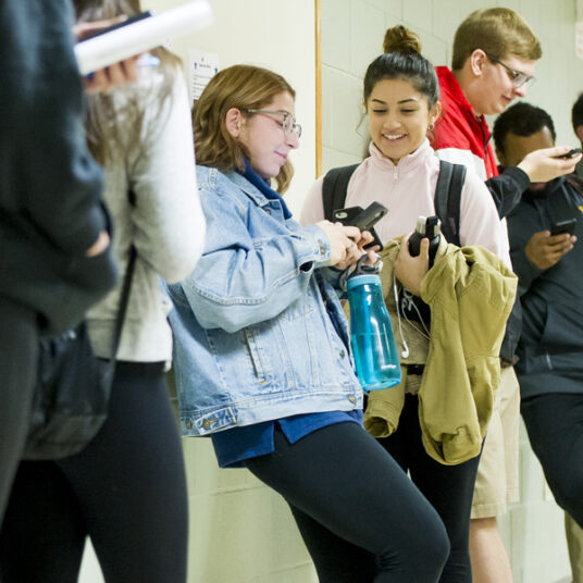 Students in hallway talking and looking at phones