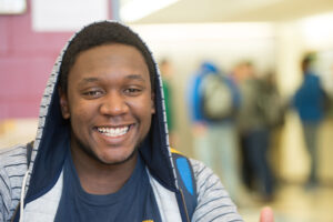 Young Black male wearing a hoodie and smiling.