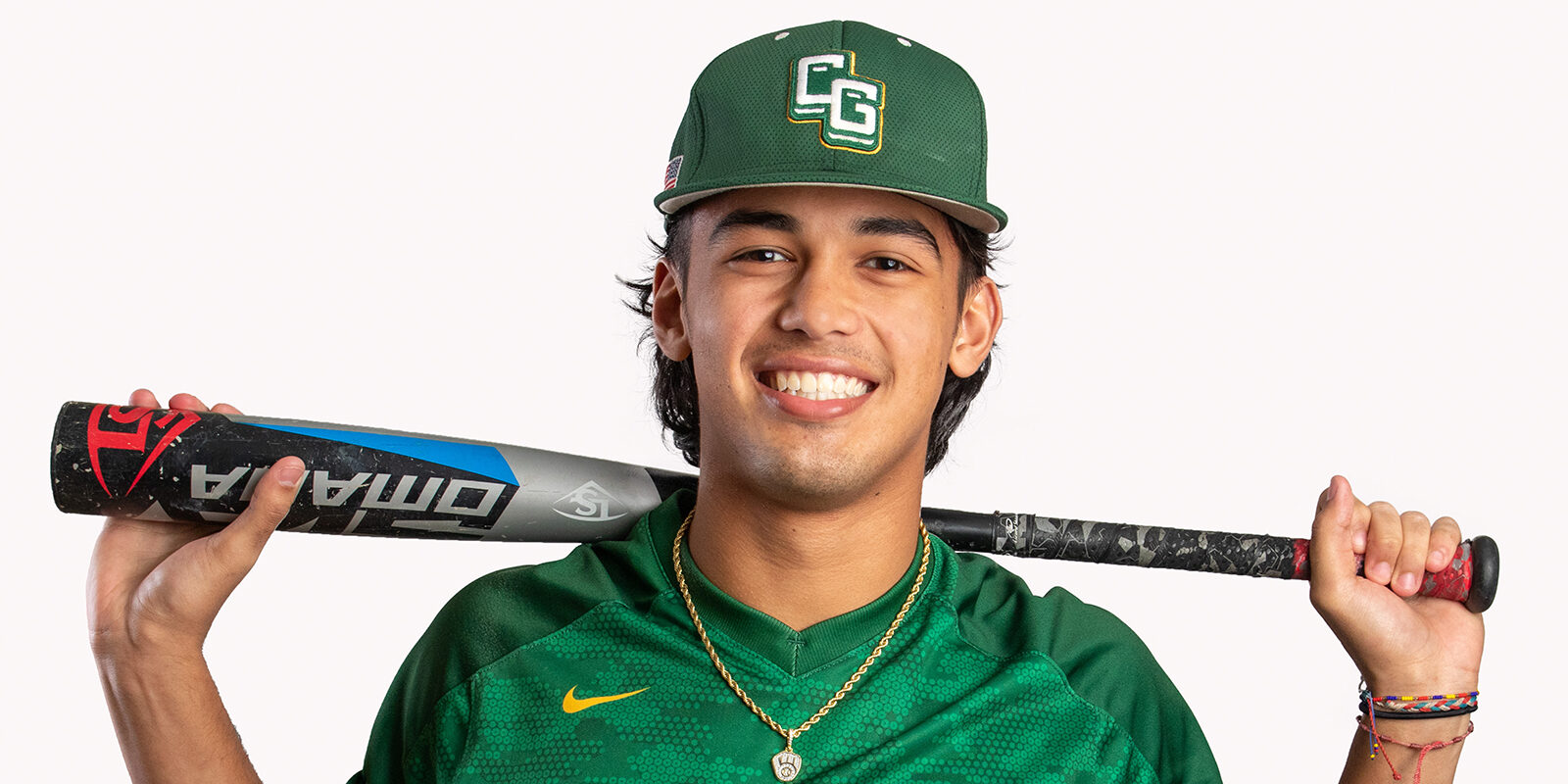 Smiling male baseball player in green hat, and green jersey with a baseball bat behind his neck.