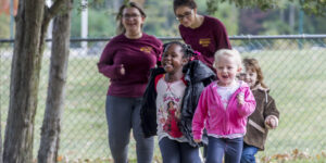 three young children running in an outdoor day care setting